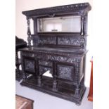 A late Victorian ebonised carved oak dresser with mirror panel back over three drawers, cupboards
