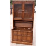 An Ercol elm "dresser", the upper section enclosed glazed doors over drawers and cupboards, on stile