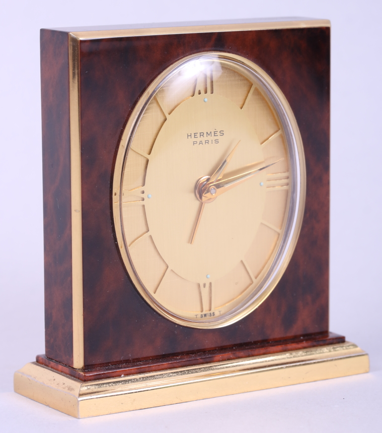 An Hermes "tortoiseshell" alarm clock with gilt dial and Roman numerals, 3" high