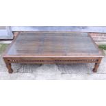 A hardwood low coffee table with glass and bamboo top, on shaped supports, 35" x 62", and an