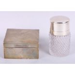 An engine turned silver cigarette box and a cut glass and silver mounted smelling salts jar