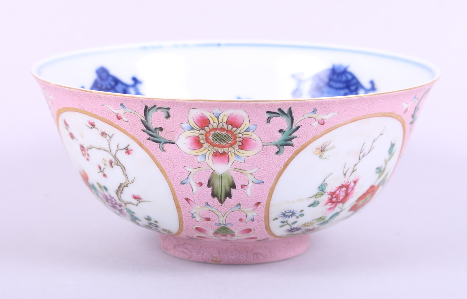 A Chinese porcelain bowl, decorated panels with trees and flowers on a pink ground, inside decorated