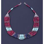 A multi-strand necklace consisting of faceted ruby, emerald and sapphire beads with metal