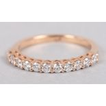 An 18ct rose gold eternity ring set eleven diamonds, ring size L