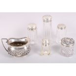 A silver cream jug with embossed floral decoration, a similar silver topped dressing table jar and