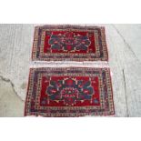 A pair of Caucasian mats with star medallions on a red ground, each 22" x 40" approx (worn damages)