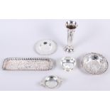 A silver tea strainer and stand, a silver pin tray, two embossed silver dishes and a silver