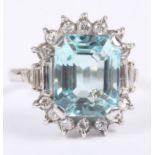 An emerald cut aquamarine ring, six carats approx, set central stone surrounded by brilliant and