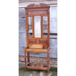 An Edwardian walnut hall stand with pierced carved and spindle decoration, fitted mirror over