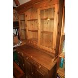 A pine dresser, the upper section with central shelves and spice drawers flanked two glazed doors,