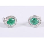 A pair of 18ct white gold, emerald and diamond ear studs