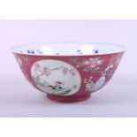 A Chinese porcelain bowl, decorated panels with animals and precious objects on a dark pink
