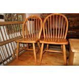 A set of four beech spindle back kitchen chairs with panel seats, on turned and stretchered