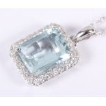 An 18ct white gold and aquamarine pendant, central emerald cut stone surrounded diamonds, on 18ct