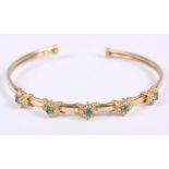 A 9ct gold and emerald bangle set brilliant accents