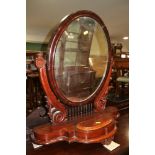 A Victorian mahogany swing frame mirror, on scrolled supports with central compartment, 24" wide (