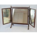 A mahogany triptych dressing toilet mirror raised over H shaped base with turned brass finials,