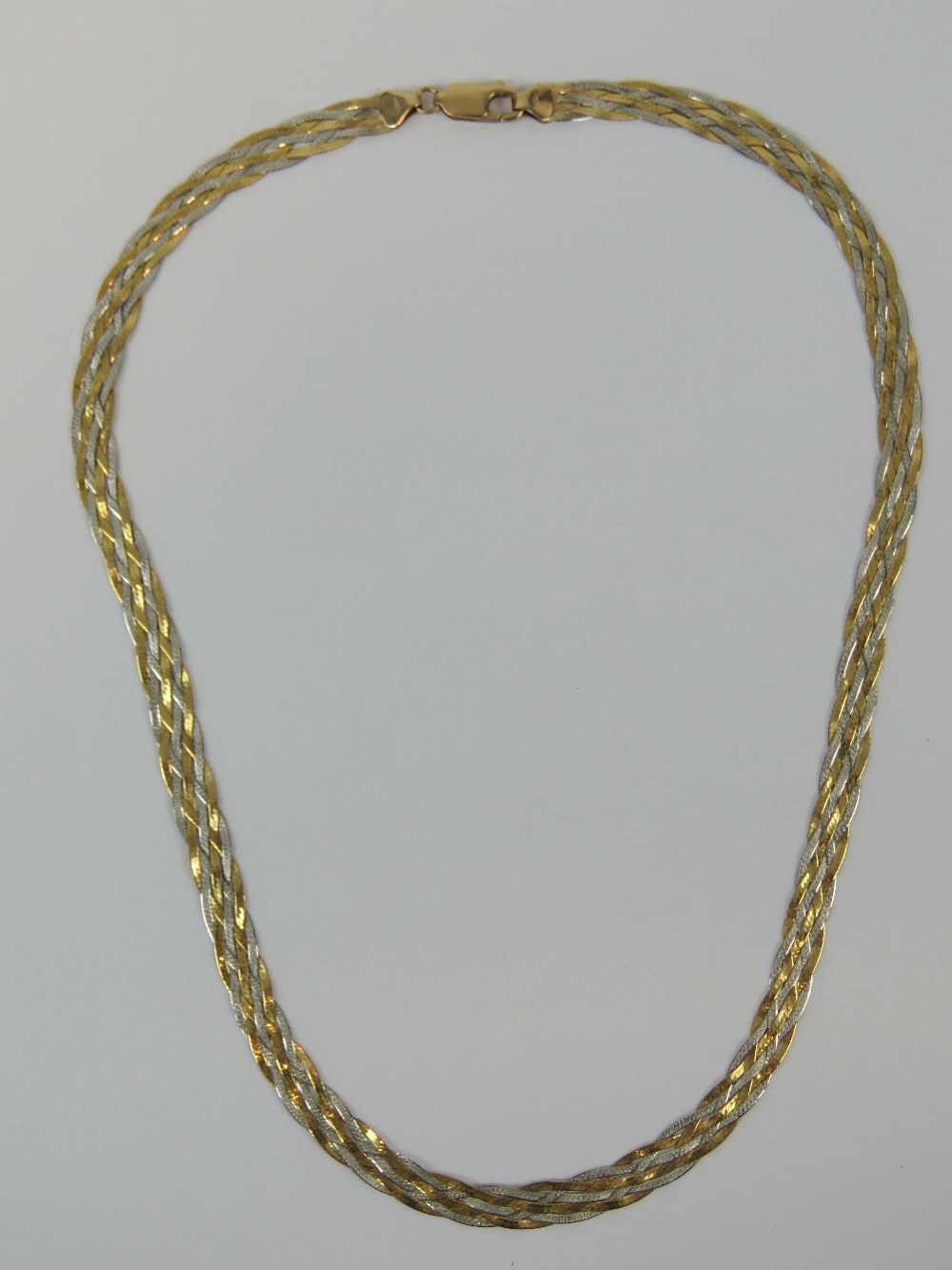 A 9ct gold necklaces having six strands of white and yellow gold woven together, hallmarked 375,
