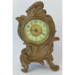 A small late Victorian boudoir clock of rococo scroll design in a gilt painted white metal case,