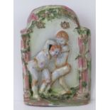 A ceramic wall plaque featuring boys fighting upon, within a foliate pillared surround, 33cm high.