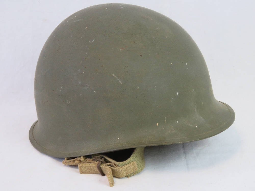 A US WWII M1 Infantry issue helmet with original liner and chinstrap having plain olive drab paint,