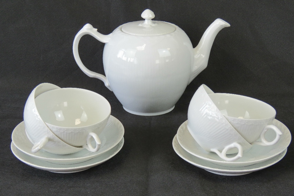 A Royal Copenhagen ivory ground teapot together with four matching cups and saucers.