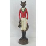 A figurine of a fox in huntsman outfit complete with red tunic and riding boots,