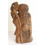 A carved wooden figure of Shou Lao, the Chinese god of longevity, holding fruit and cane,