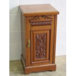 An Edwardian pot cupboard having machine carved door opening to reveal compartment within,