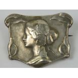 An Art Nouveau white metal brooch bearing the portrait of a female,