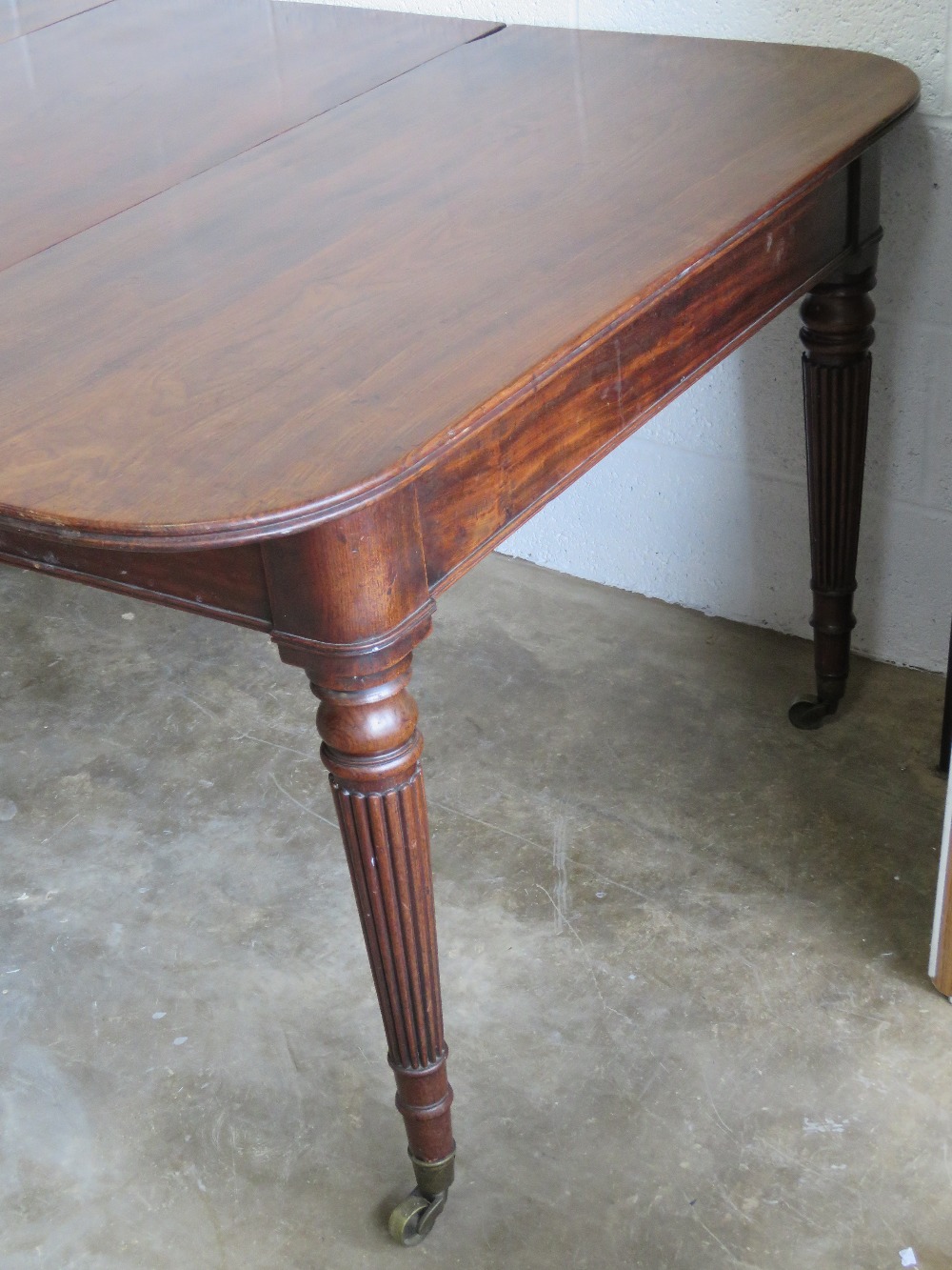 A 19th century mahogany pull out extending dining table having two leaves raised over reeded legs - Image 2 of 2