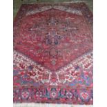 A large red ground hand woven Iranian woollen carpet having geometric decoration, 330 x 256cm.