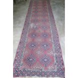 A vintage woollen red ground runner having geometric design upon, 396 x 120cm. Slightly worn.