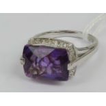 A silver cocktail ring having large rectangular faceted amethyst and white stones set to shoulders,