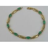 A 10ct gold diamond and emerald bracelet having eight oval cut emeralds with pairs of diamonds