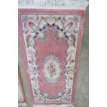 A contemporary Oriental style woolen and silk rug, pink ground with floral decoration, 185 x 95cm.