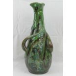 A stylised green ground handmade vase of large proportions having three proud foliate handles with