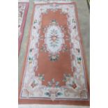 A contemporary Oriental style woolen and silk rug, orange ground with floral decoration, 185 x 95cm.