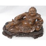 A finely detailed wooden carving of a recumbent deity, fish in hand,