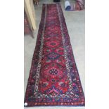 A red ground woollen runner having geometric decoration upon, measuring 520 x 102cm.