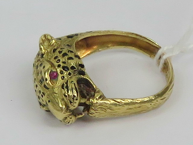 An unusual 18ct gold leopards head ring having black enamel spots and faceted garnet eyes,