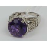 A silver cocktail ring having large round faceted amethyst and white stones set to shoulders,