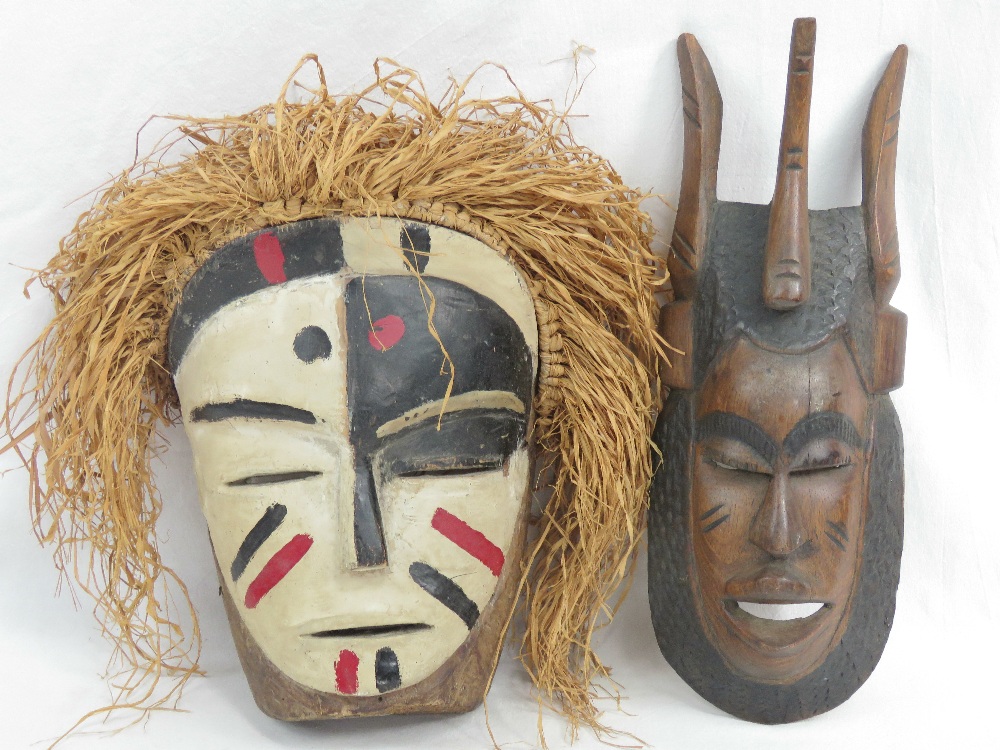 A 20th century African tribal mask painted in whites, blacks and red, having grass 'hair,