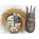 A 20th century African tribal mask painted in whites, blacks and red, having grass 'hair,