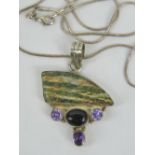A silver and hardstone pendant having triangular green banded stone over three faceted purple