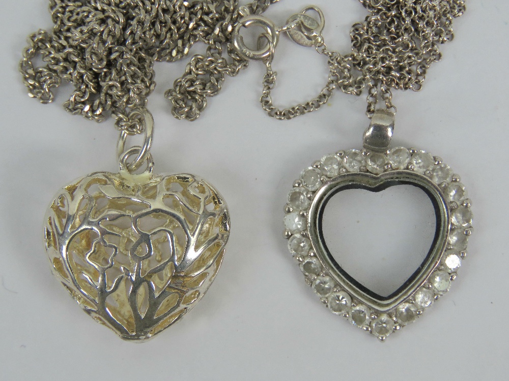 A silver heart shaped pendant having white stone border and glass central panel,