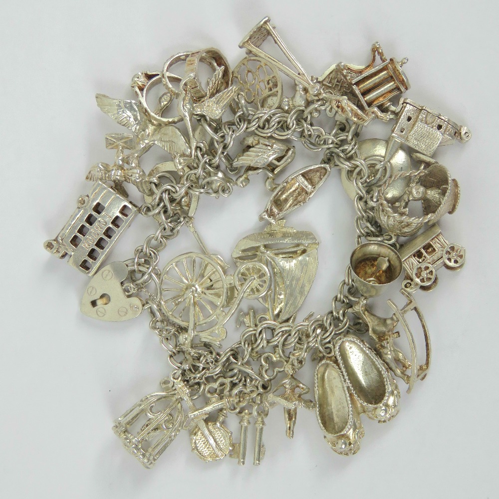 A silver charm bracelet having double curb link chain and heart padlock clasp stamped silver,