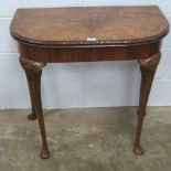 A walnut quarter veneered fold over games table c1930s, lid lifting to reveal baise top,