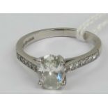 A platinum and diamond ring having central oval claw set diamond of approx 0.