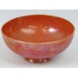 A Ruskin orange lustre bowl, raised on a plain foot and with impressed marks, 10cm diameter.